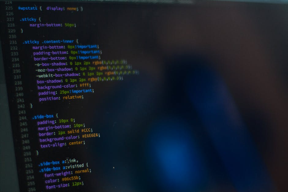 The image displays a close-up view of a computer screen showing lines of computer code in a text editor. The code is highlighted with various colors, including green, yellow, blue, purple, and orange,